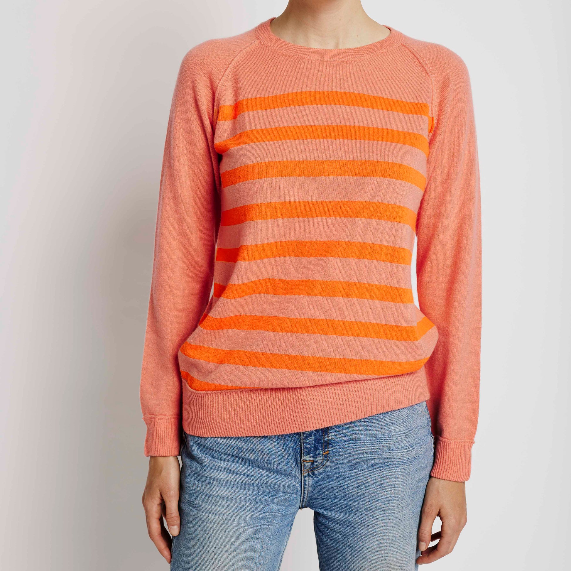 Alabaste Le Breton cashmere sweater in peach with orange stripes, front view on model wearing size small, featuring horizontal stripes and raglan sleeves, made from 100% Mongolian cashmere.