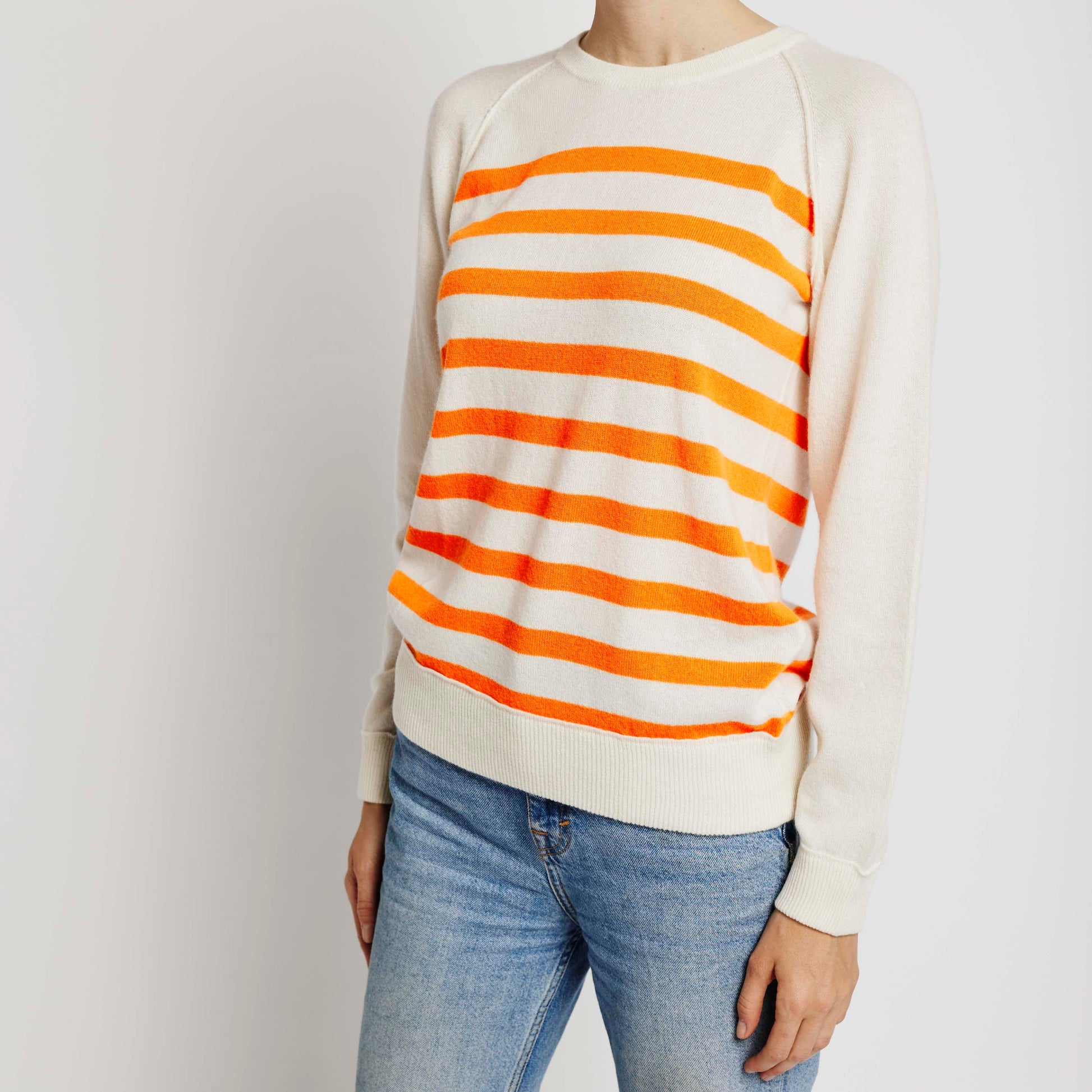 Alabaste Le Breton cashmere sweater in orange and cream, front view on model wearing size small, featuring horizontal stripes and raglan sleeves, made from 100% Mongolian cashmere.